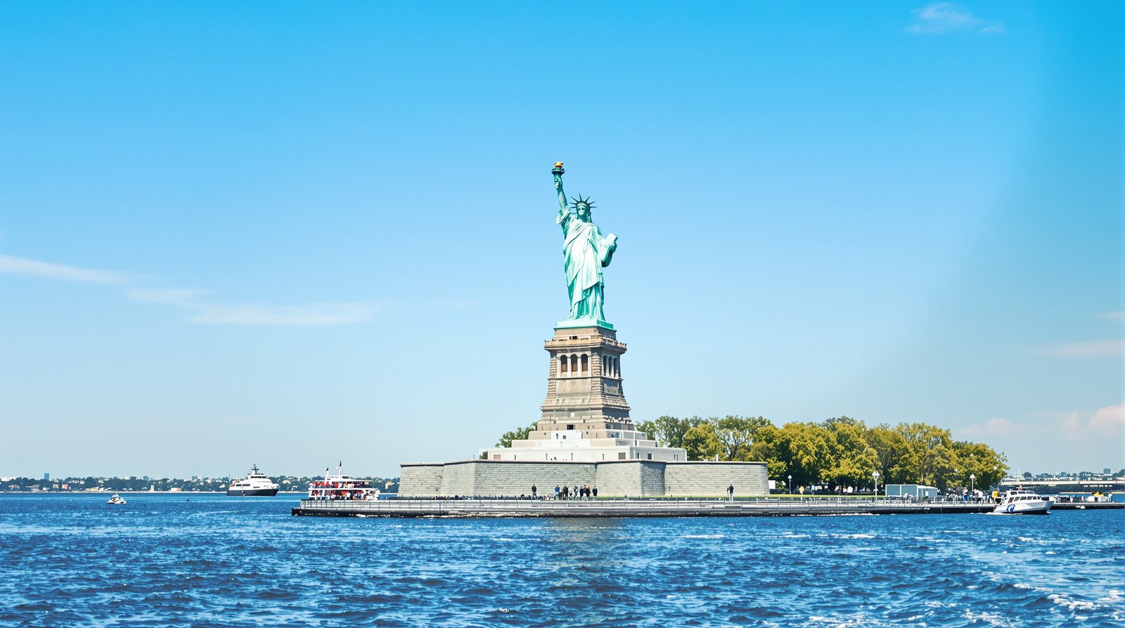 The Statue of Liberty standing tall against a clear blue sky, viewed from a ferry on the water