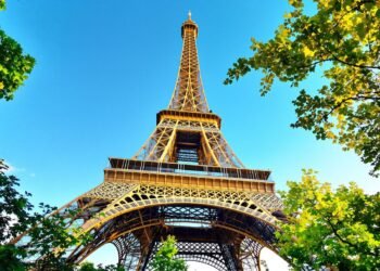 Eiffel Tower with lush trees and blue sky.