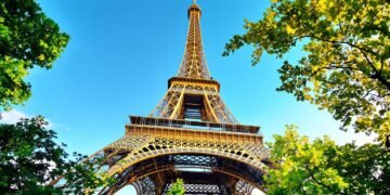 Eiffel Tower with lush trees and blue sky.