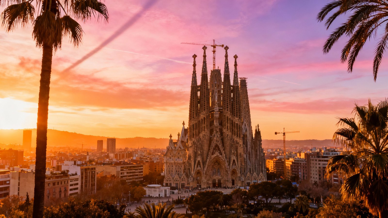 Panoramic view of the Barcelona skyline at sunset with the Sagrada Familia prominent against the vibrant sky