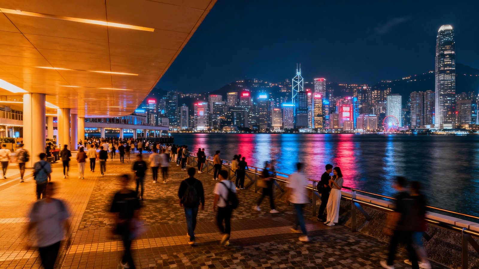 The vibrant Tsim Sha Tsui promenade at night, with crowds enjoying the view of the Hong Kong Island skyline across the water