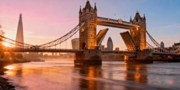 Cinematic wide-angle view of Tower Bridge at sunrise with the London skyline in the background